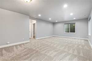 Non-Staged basement family room with light carpet and a textured ceiling