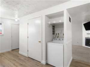 Clothes washing area with washer / dryer and light hardwood / wood-style flooring