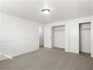 Unfurnished bedroom with light carpet and multiple closets