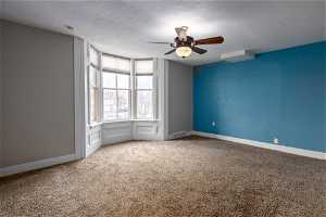 Spare room featuring light carpet, a textured ceiling, and ceiling fan