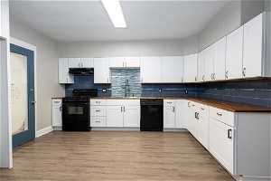Kitchen featuring backsplash, sink, black appliances, and light wood-type flooring