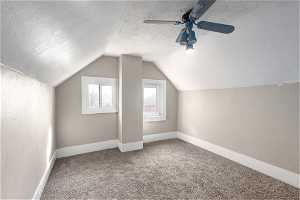 Bedroom with carpet flooring, ceiling fan, lofted ceiling, and a textured ceiling