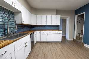 Kitchen with butcher block counters, sink, light hardwood / wood-style floors, dishwasher, and backsplash
