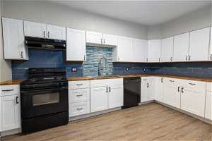 Kitchen featuring tasteful backsplash, wooden counters, sink, and black appliances