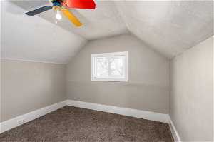 Bedroom featuring ceiling fan, a textured ceiling, lofted ceiling, and carpet