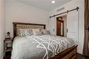 Bedroom featuring dark hardwood / wood-style flooring and a barn door