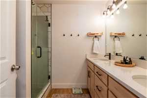 Bathroom featuring walk in shower, dual vanity, and wood-type flooring