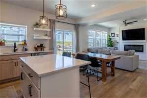 Kitchen with sink, a kitchen island, hanging light fixtures, ceiling fan, and light hardwood / wood-style floors