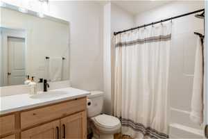 Full bathroom featuring shower / bath combo, vanity with extensive cabinet space, and toilet