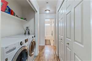 Laundry room featuring washing machine and dryer and light hardwood / wood-style flooring