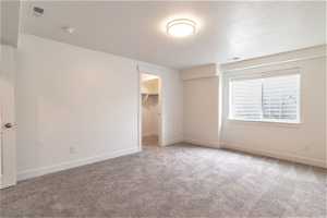 Unfurnished bedroom featuring a closet, light carpet, a spacious closet, and a textured ceiling