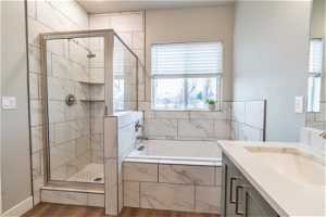 Bathroom featuring hardwood / wood-style floors, vanity, and plus walk in shower