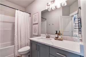 Full bathroom with shower / bathtub combination with curtain, oversized vanity, and toilet
