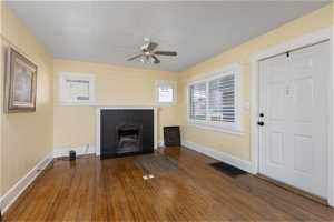 Unfurnished living room featuring ceiling fan, a brick fireplace, and dark hardwood / wood-style flooring