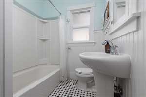 Bathroom with tile flooring, shower / bath combination with curtain, and toilet