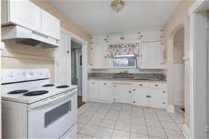 Kitchen featuring sink, custom exhaust hood, white electric range oven, and white cabinetry