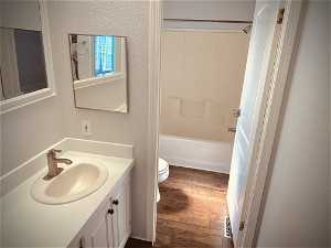 Full bathroom with toilet, bathing tub / shower combination, oversized vanity, and hardwood / wood-style flooring