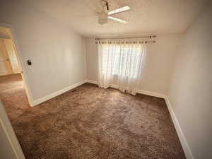 Carpeted empty room with a textured ceiling and ceiling fan