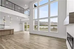Unfurnished living room featuring plenty of natural light, light hardwood / wood-style floors, a towering ceiling, and a mountain view