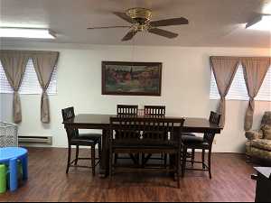 Dining room with ceiling fan, a baseboard heating unit, and dark wood-type flooring