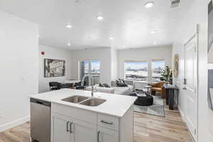 Kitchen with a kitchen island with sink, sink, dishwasher, and light hardwood / wood-style floors