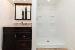 Bathroom featuring walk in shower, vanity, and hardwood / wood-style flooring