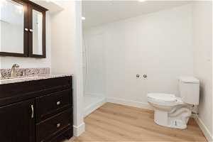 Bathroom featuring vanity, hardwood / wood-style flooring, toilet, and a shower