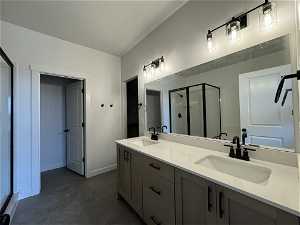 Bathroom with tile flooring, large vanity, a shower with shower door, and dual sinks