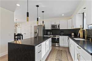 Kitchen with decorative light fixtures, a notable chandelier, appliances with stainless steel finishes, and a center island