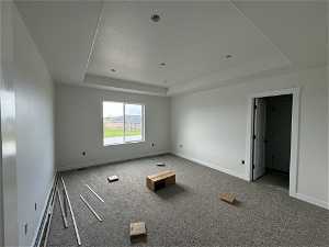 Spare room with a textured ceiling, a raised ceiling, and carpet flooring