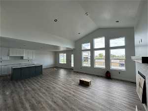 Unfurnished living room with high vaulted ceiling, hardwood / wood-style flooring, and a brick fireplace