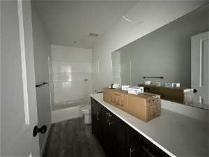 Full bathroom featuring hardwood / wood-style floors, tub / shower combination, vanity, and toilet