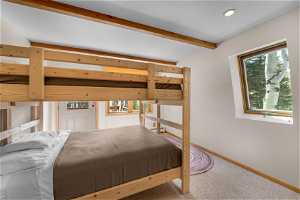 Carpeted bedroom featuring lofted ceiling with beams.