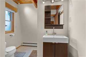 Bathroom with wood ceiling, vanity, tile flooring, a baseboard radiator, and toilet.