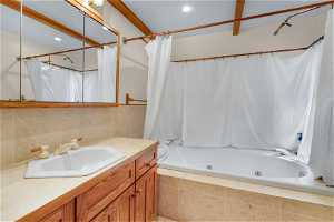 Bathroom featuring vanity and shower / bathtub combination with curtain.