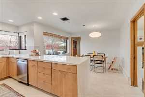 Kitchen featuring decorative light fixtures, light brown cabinets, stainless steel dishwasher, and light tile floors
