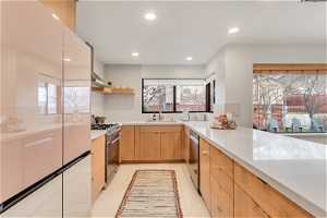Kitchen featuring quartz backsplash, appliances with stainless steel finishes, sink, light brown cabinets, backsplash, and light tile floors