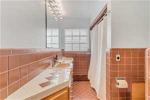 Bathroom with midcentury tile walls, double vanity, tile floors, and backsplash