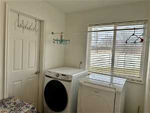 Clothes washing area with washer and dryer and door to half bath