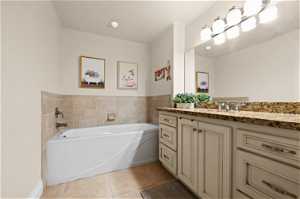Bathroom featuring tile flooring, a washtub, and vanity
