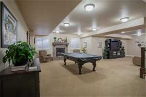 Game room featuring a stone fireplace, pool table, and light colored carpet