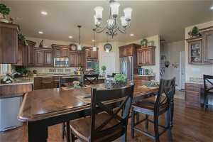 Kitchen featuring decorative light fixtures, stainless steel appliances, a chandelier, and dark hardwood / wood-style floors