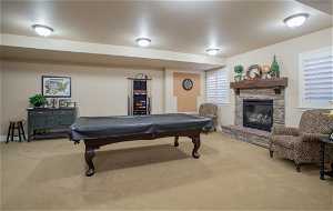 Rec room featuring billiards, light carpet, and a stone fireplace