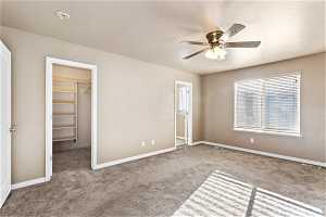 Unfurnished bedroom featuring light carpet, a spacious closet, a closet, and ceiling fan