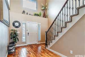 Entryway featuring hardwood flooring, a high ceiling, and a healthy amount of sunlight featuring grand staircase