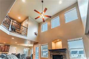 Living room featuring a fireplace, a high ceiling, and ceiling fan with beautiful view of balcony/loft staircase