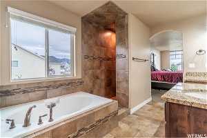 Bathroom featuring tiled tub, tile flooring, and vanity