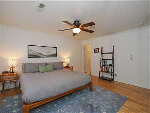 Bedroom with light hardwood / wood-style floors, ornamental molding, and ceiling fan