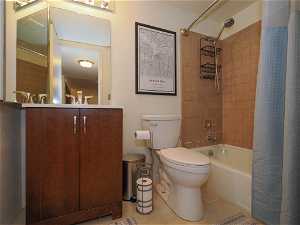 Full bathroom with shower / bath combo with shower curtain, toilet, tile floors, and vanity
