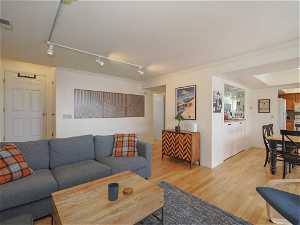 Living room with light hardwood / wood-style flooring, rail lighting, and crown molding